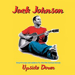 The cover of Upside Down by Jack Johnson features a simple, warm-toned photograph that reflects his laid-back style. The image shows Johnson sitting barefoot on the ground, holding an acoustic guitar, waring a simple blue jean red shirt combo.